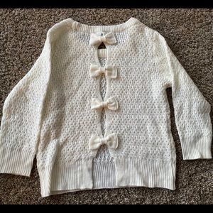 White sweater with bows in back.